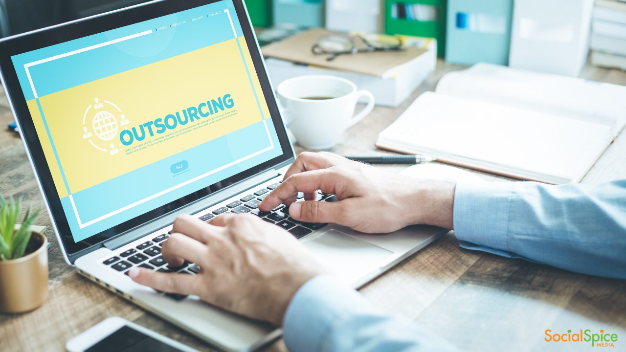 man typing on his laptop with the words "outsourcing" on the screen